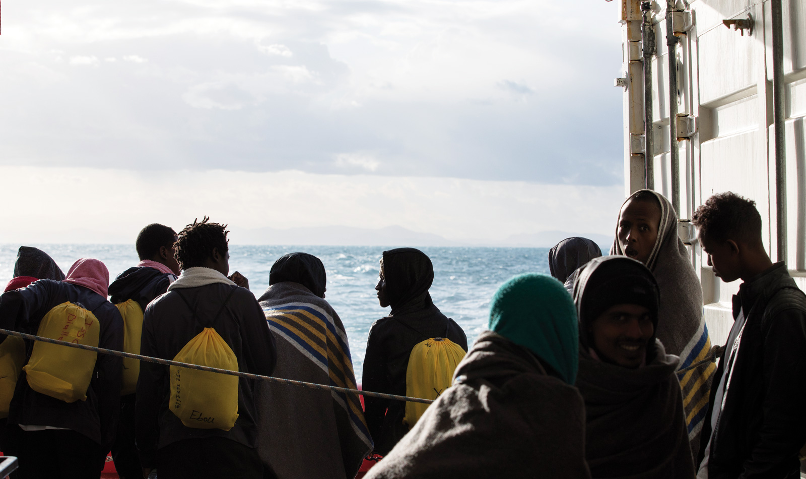 En samling med människor blickar ut över havet.