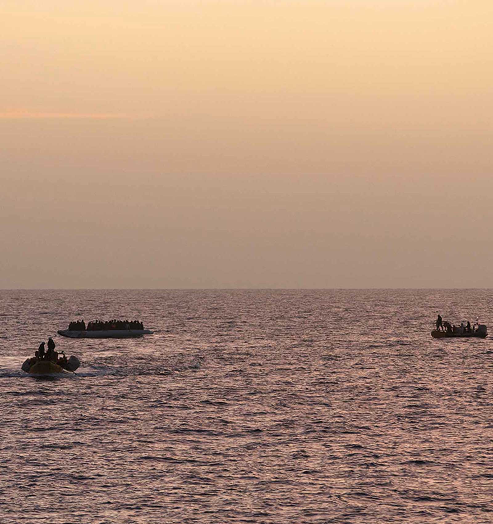 Tre båtar syns på havet, i solnedgången